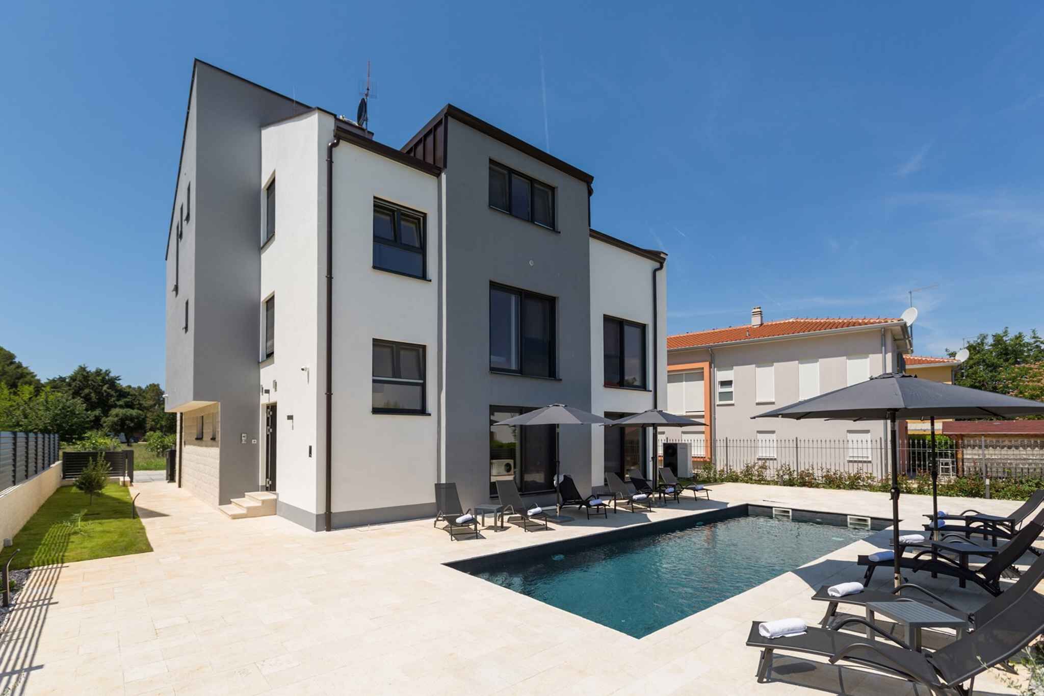 A modern two-story house with a swimming pool, outdoor seating, and a well-maintained garden.