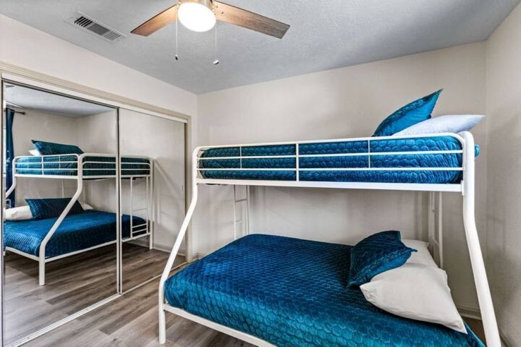 A bunk bed room with a ceiling fan, a mirror, and a wardrobe.