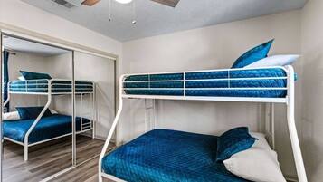 A bunk bed room with a ceiling fan, a mirror, and a wardrobe.