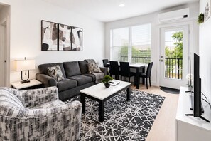 A modern living room with a sofa, armchair, coffee table, and dining area. - Modern Luxury Suite • Downtown Hot Springs (Hot Springs)