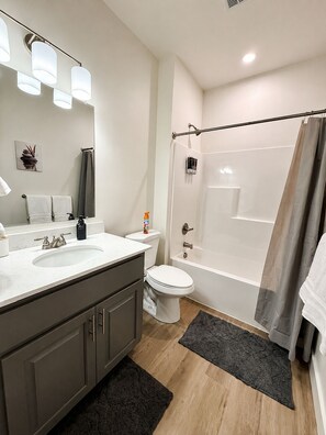 A modern bathroom with a sink, toilet, and bathtub. - Modern Luxury Suite • Downtown Hot Springs (Hot Springs)