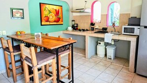 A compact kitchen with a dining area, a microwave, a sink, and a gas stove.