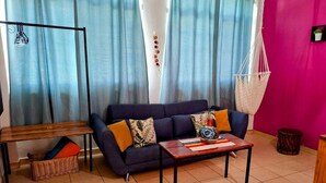 A living room with a sofa, a coffee table, a hanging chair, a small drum, and a basket.