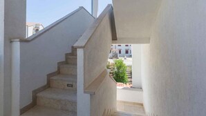 Una escalera que lleva a un balcón con vistas a un edificio y algo de vegetación.