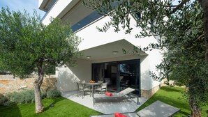 A modern house with a patio area, a dining table, and a seating arrangement. - Holiday apartment with pool and air conditioning (Sv. Filip i Jakov)