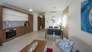 A modern kitchen with wooden cabinets, a built-in oven, and a dining area with a table and chairs. - Holiday apartment with pool and air conditioning (Sv. Filip i Jakov)