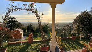 Blick auf einen Garten mit einer Pergola, Blumentöpfen und blauem Himmel.