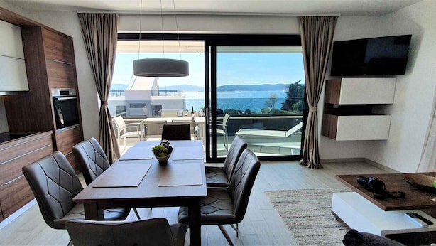 Ett modernt hotellrum med en matplats, ett kök och en balkong med utsikt över havet.