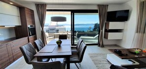 Habitación de hotel moderna con zona de comedor, cocina y balcón con vistas al mar.