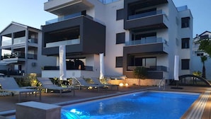 Ett modernt hotell med en swimmingpool, solstolar och ett väl upplyst utomhusområde.