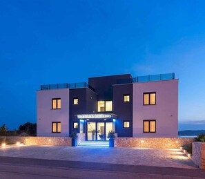 Ein modernes Hotel mit Natursteinfassade, einem markanten Eingangsbereich und freiem Blick auf die umliegende Landschaft.