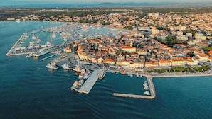 Ett flygbildsbild av en kuststad med en småbåtshamn, byggnader och en hamn.