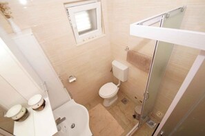Uma casa de banho moderna com sanita, bidé e cabine de duche em vidro.