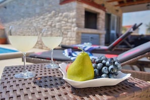 A table with two glasses of white wine, a pear, and a bowl of blueberries. - Holiday home with terrace and pool (Vela Luka)