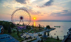 Ein Riesenrad bei Sonnenuntergang mit Blick auf das Wasser und ferne Berge.