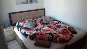 Ein Bett mit blumigem Überwurf, zwei Kissen und einem hölzernen Kopfteil.