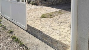 A two-story building with a stone facade, a gated entrance, and a paved courtyard. - Holiday apartment with barbecue facilities and terrace (Vir)