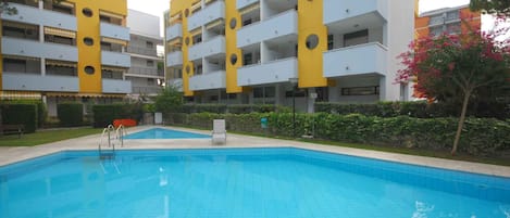 A swimming pool surrounded by a modern building with balconies.