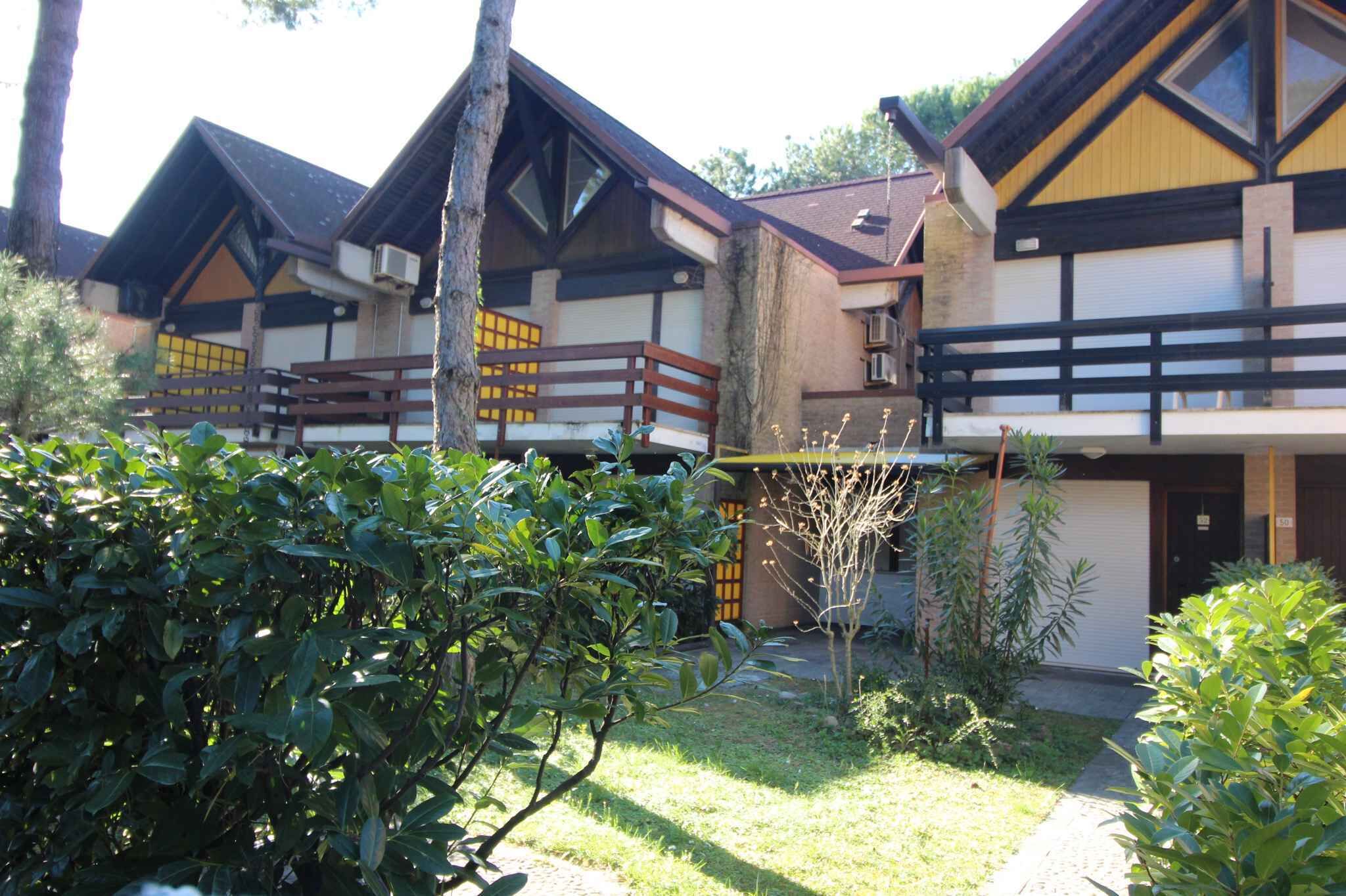 Une rangée de chalets traditionnels en bois, dotés de balcons, et entourés d’une végétation luxuriante et bien entretenue.