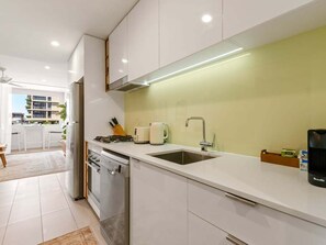 A modern kitchen with white cabinets, a stainless steel range, a sink, and a coffee maker. - Modern South Brisbane Apt w/ Pool & Gym (Brisbane)