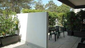 Un espace patio agrémenté d’une cloison blanche, de sièges d’extérieur et de plantes en pot.