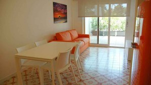 Un coin repas comprenant une table et des chaises, un canapé et une grande fenêtre donnant sur un paysage verdoyant.