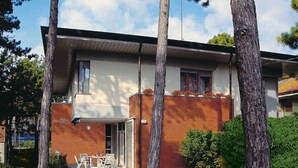 A modern two-story house with a flat roof, a covered patio, and a small garden. - Holiday apartment mit Terrasse (Lignano Sabbiadoro)