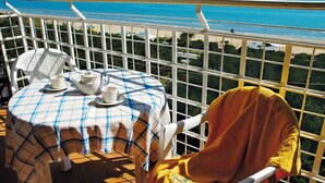 A balcony with a table set for two, overlooking a beach. - Holiday apartment mit Meerblick (Lignano Sabbiadoro)