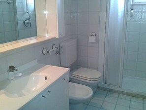 Ein Badezimmer mit weißem Waschbecken, WC und Dusche.