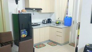 Una cucina funzionale con frigorifero, fornello e lavello. Due sedie e un tavolo da pranzo.