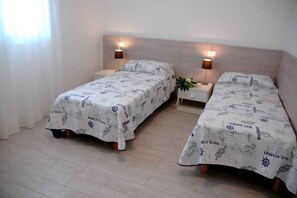 Two single beds with matching headboards and nightstands, each with a wall-mounted lamp. - Holiday apartment mit Terrasse (Lignano Sabbiadoro)