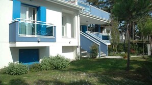 Ein modernes Gebäude mit Balkon, Treppe und einer kleinen Gartenanlage.