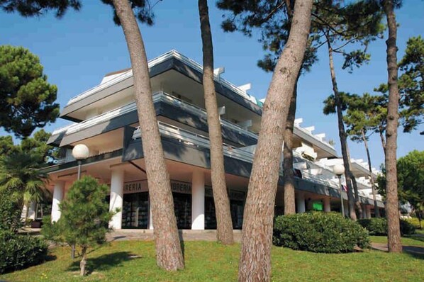 A multi-story hotel with a modern architectural design, featuring a flat roof and large windows. - Holiday apartment with large corner terrace (Lignano Sabbiadoro)