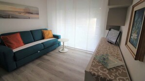 Un soggiorno con un divano verde acqua, un tavolino bianco e una TV su un mobile.