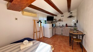 Een compacte kamer met een bed, een klein tafeltje en een kitchenette.