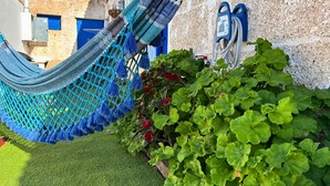 Een hangmat bevestigd aan een muur, groene planten en een blauwe deur.