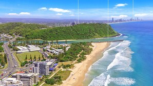 Vista aérea de uma área costeira com praia, estrada e edifícios.
