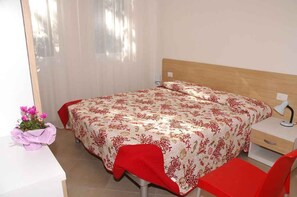 A bedroom with a bed, a desk, a chair, and a nightstand. - Holiday apartment mit Terrasse (Lignano Sabbiadoro)