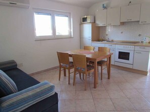 Un espai habitable compacte amb zona de menjador, petita cuina i sofà.