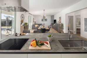 Une cuisine moderne dotée d’un grand îlot central, d’un coin repas avec une table et des chaises, et offrant une vue sur l’extérieur.