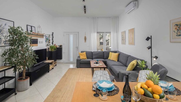 A modern living room with a sofa, coffee table, and a dining area with fruit and glassware. - Holiday apartment with terrace and air conditioning (Poreč)