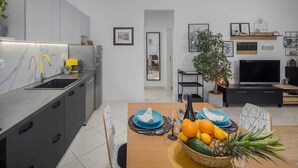 A modern kitchen with a built-in sink and a dining area with a table set for two. - Holiday apartment with terrace and air conditioning (Poreč)