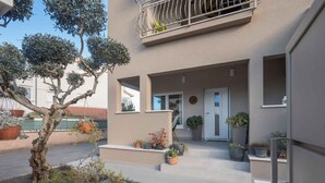A modern building with a balcony, potted plants, and a small table. - Holiday apartment with terrace and air conditioning (Poreč)