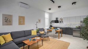 A modern living room with a grey sofa, a wooden coffee table, and a dining area with a small table and chairs. - Holiday apartment with terrace and air conditioning (Poreč)