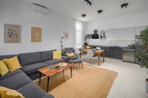 A modern living room with a grey sofa, a wooden coffee table, and a dining area with a small table and chairs. - Holiday apartment with terrace and air conditioning (Poreč)