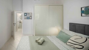 A bedroom with a bed, pillows, a bedside table, and a wardrobe. - Holiday apartment with terrace and air conditioning (Poreč)