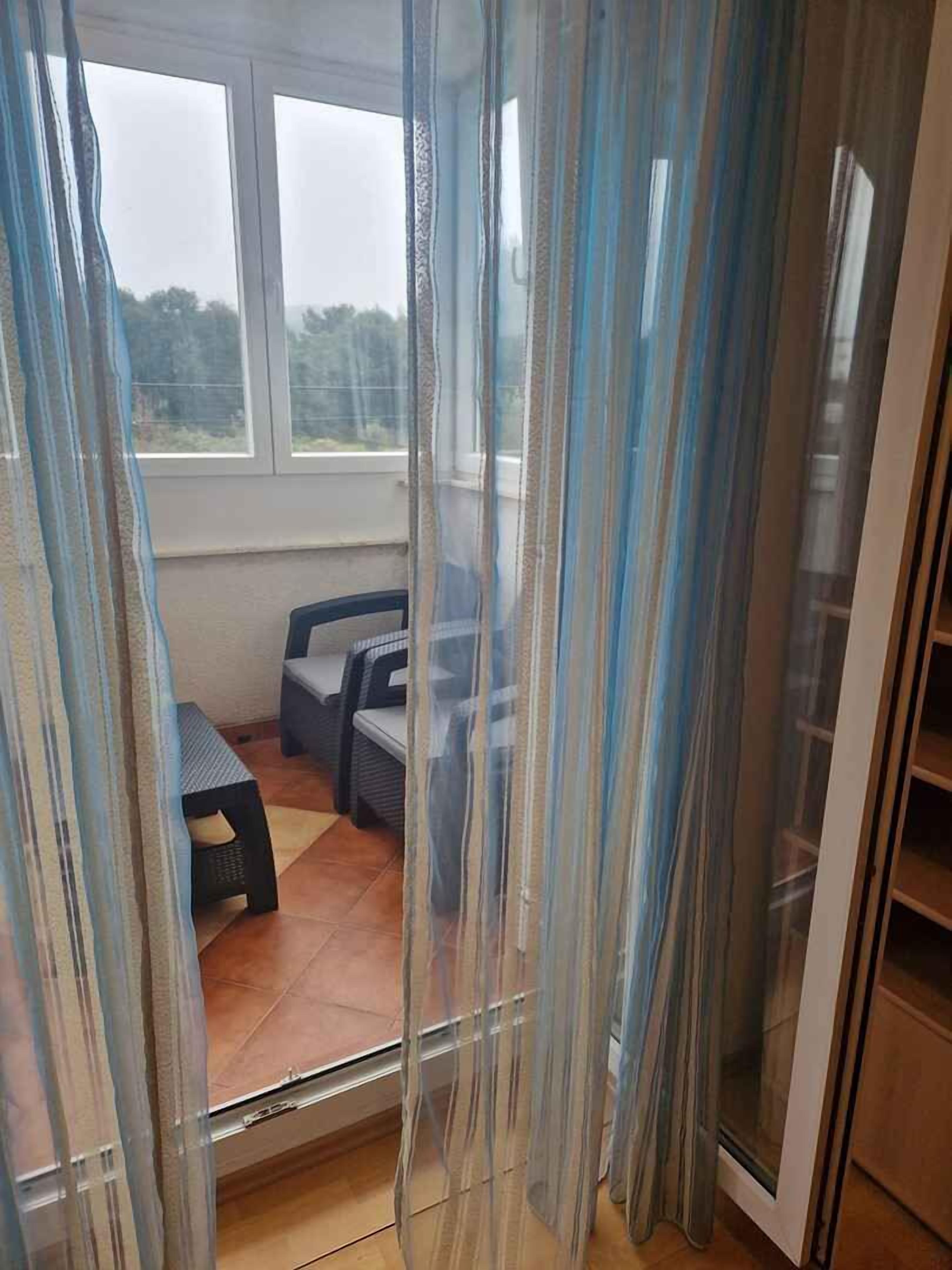 Ein Zimmer mit Blick durch ein Fenster, eine Bank und ein Stuhl.