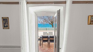 Ein Durchgang zu einem Balkon mit Blick auf das Meer und einen Baum.