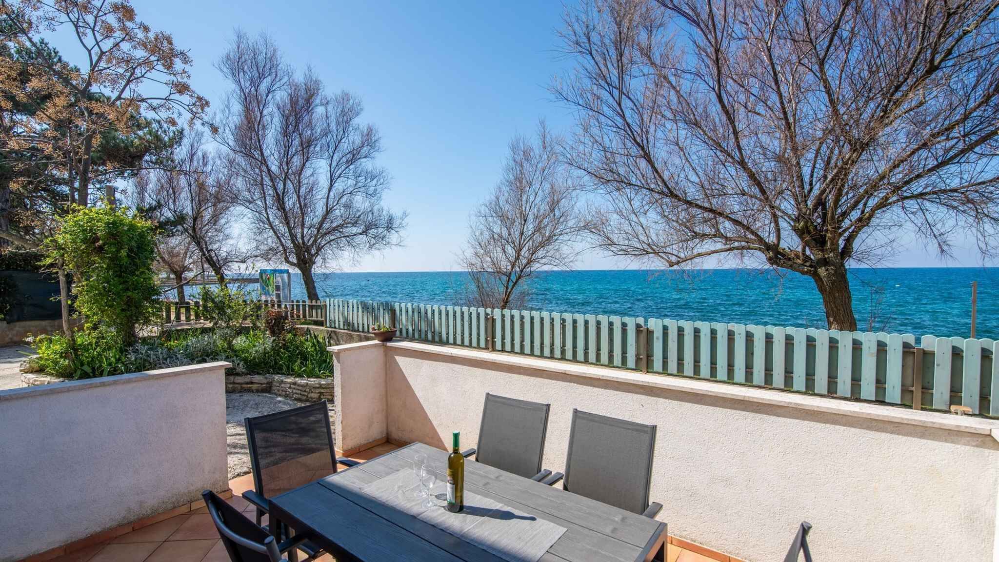Une terrasse extérieure avec une table et des chaises, donnant sur une étendue d’eau et bordée d’une clôture en bois.