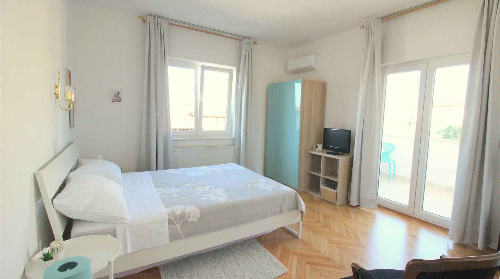 A bedroom with a bed, a TV, and a window.